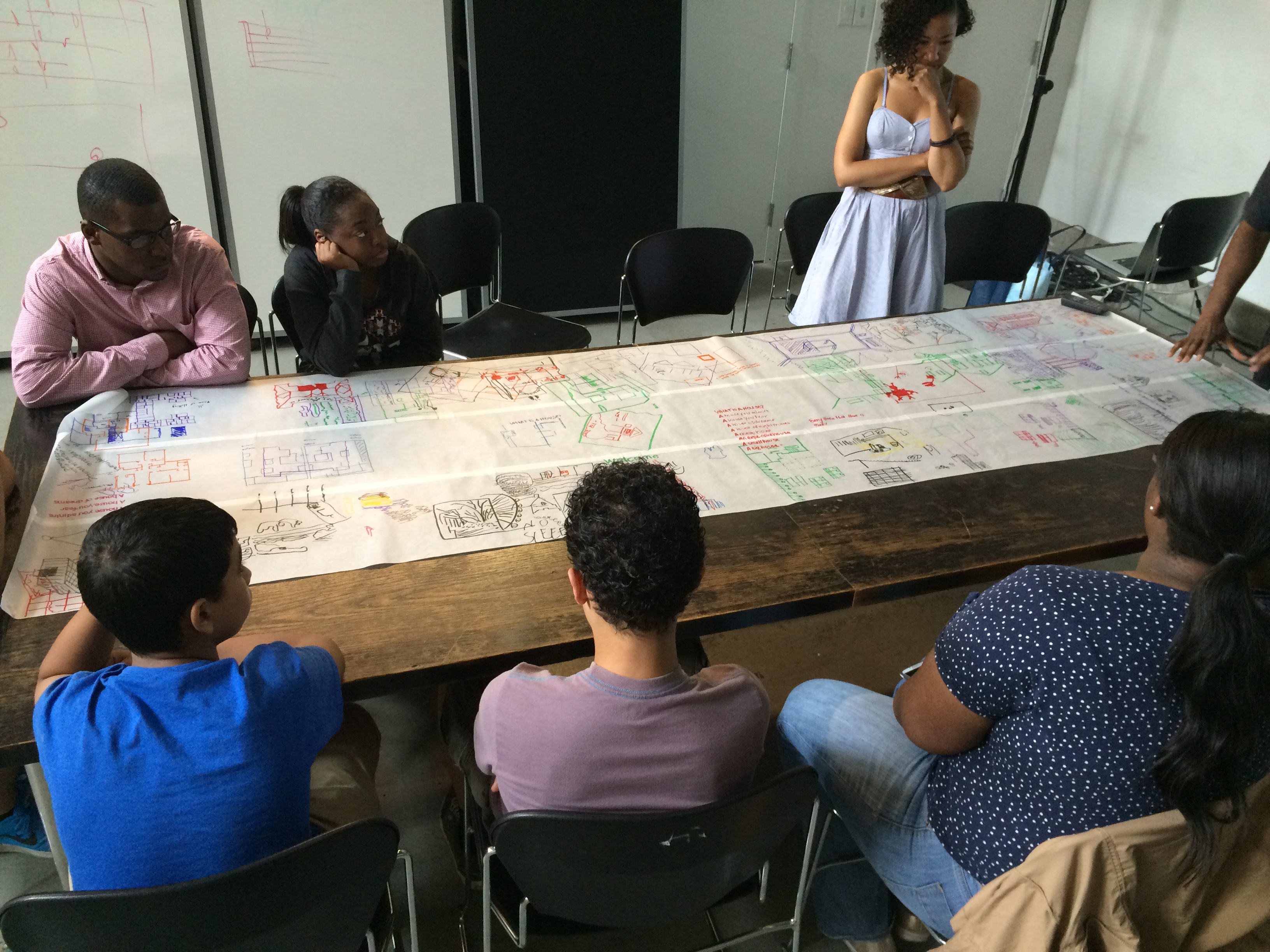 Students gathered around a table over a drawing